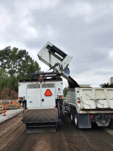 Truck unloading asphalt for roadwork.